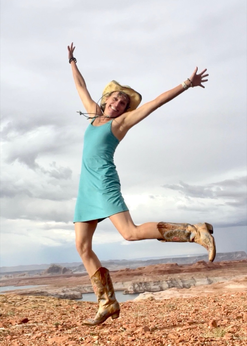 Kathy Johnson jumping in boots on a desert overlook.