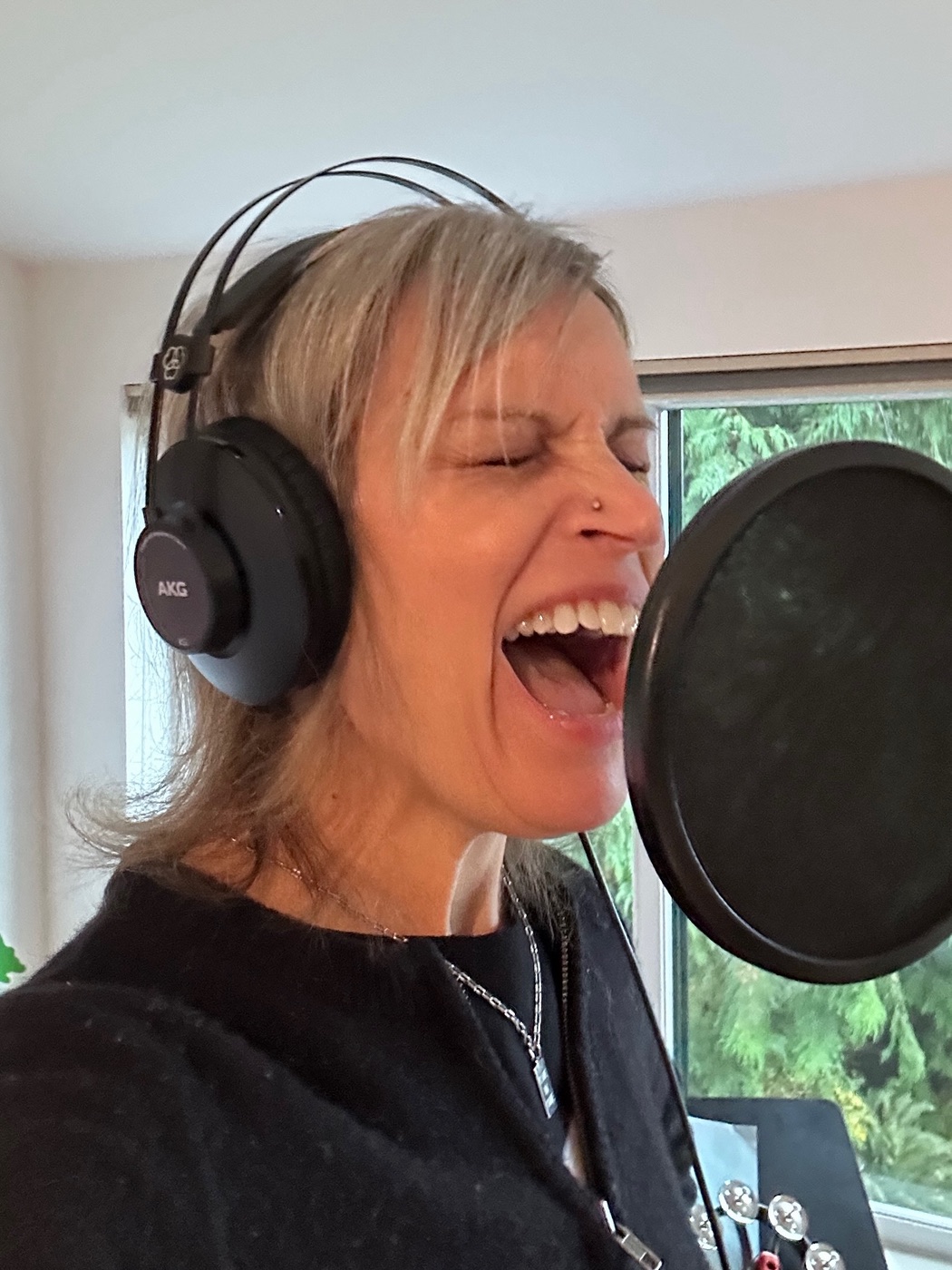 Kathy Johnson singing into a studio microphone while wearing headphones.